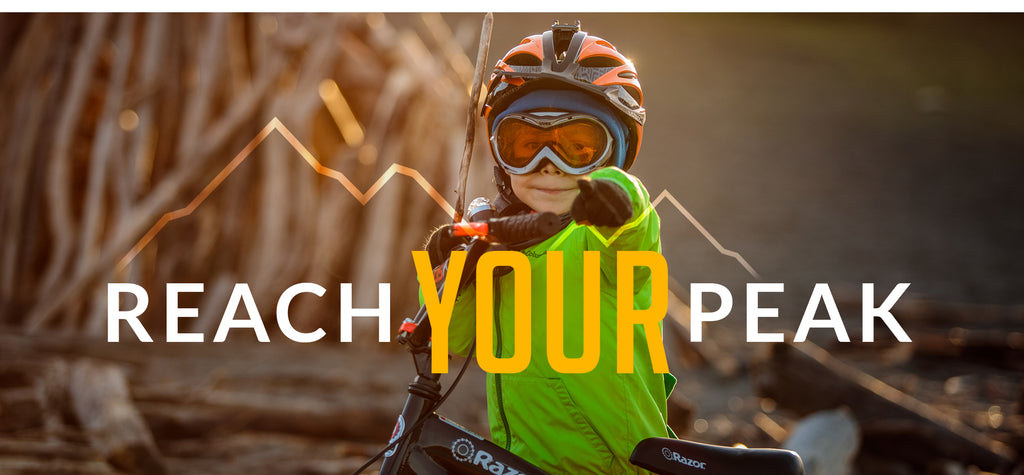 REACH YOUR PEAK - Mountain Graphic Behind Headline - Little Boy in Capstone gear pointing out towards you